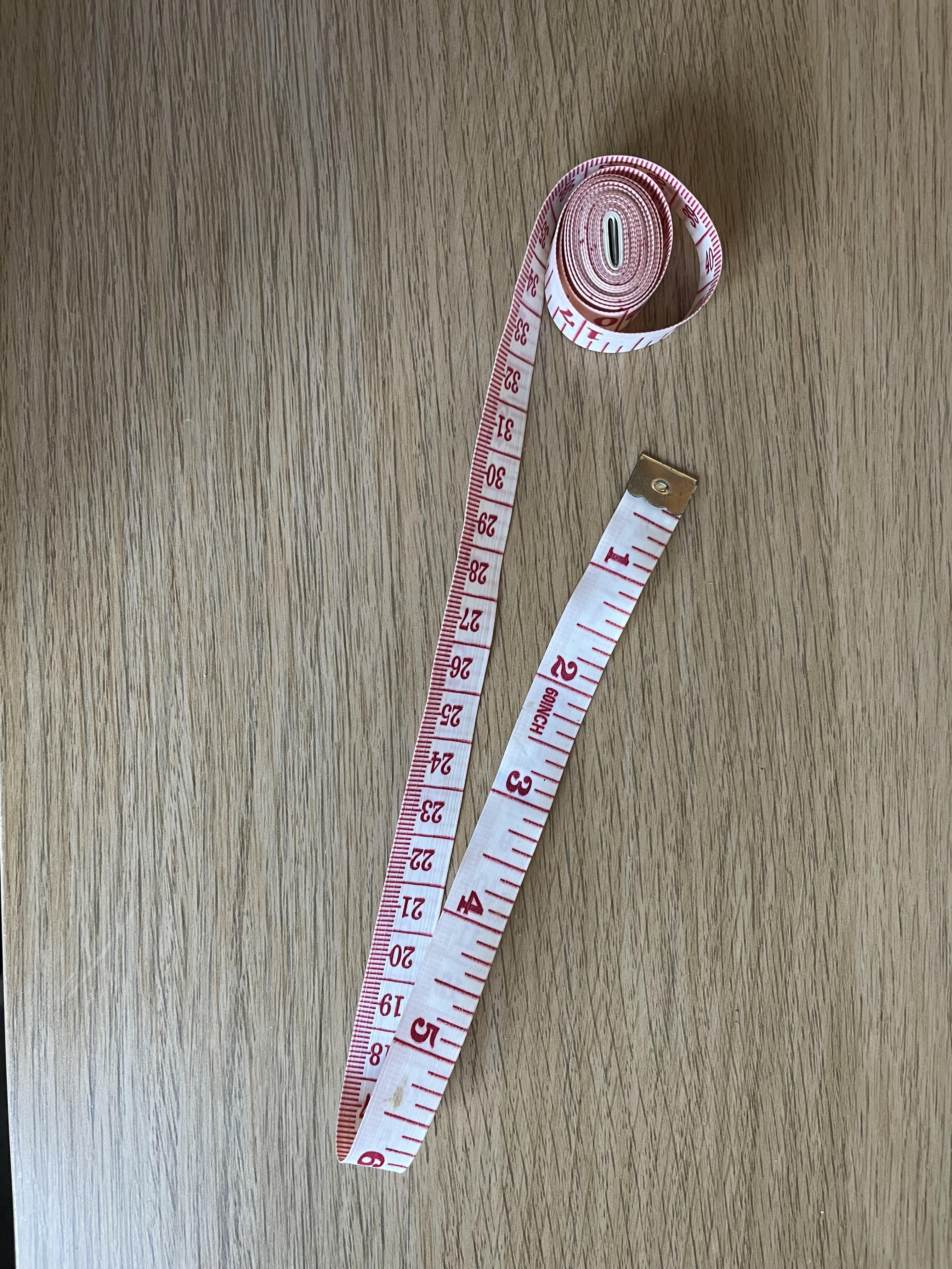 a measuring tape and a tape measure sitting on a table top next to each other on a wooden surface