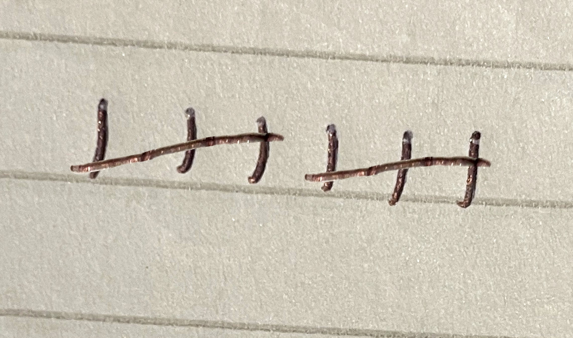 a close up of a metal hook on the side of a building with nails sticking out of the side of it