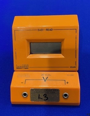 a close up of an orange clock on a blue surface with a blue background and a black clock on the front of the clock
