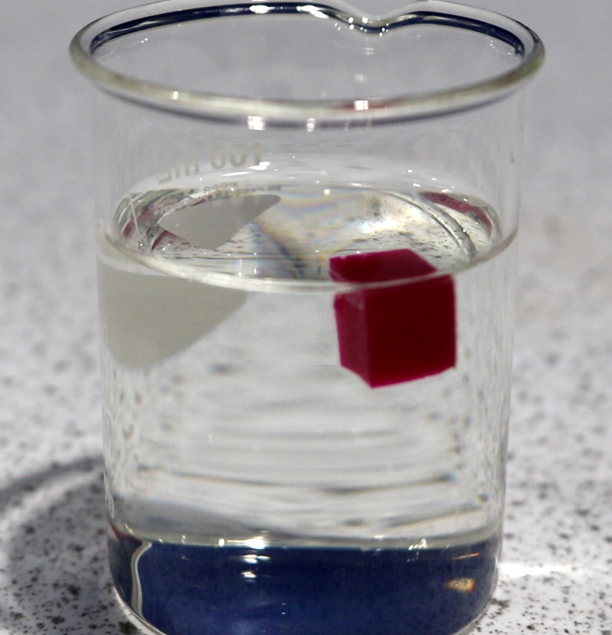 a glass filled with water and a red square in the middle of the glass is half filled with water and half filled with water
