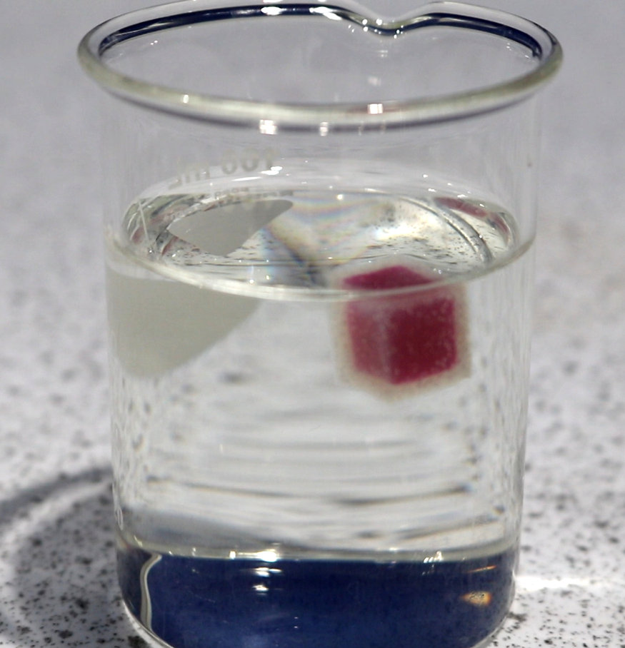 a glass filled with water and a red object in the middle of the glass is half filled with water and half filled with water