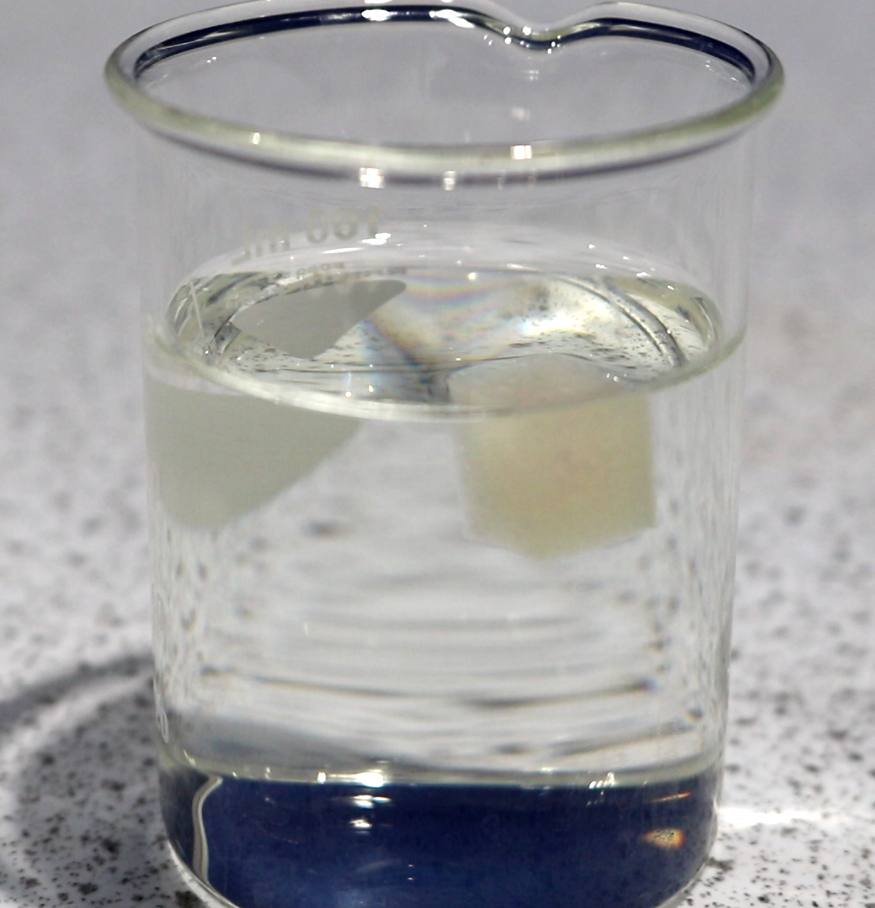 a glass filled with water on top of a white counter top next to a blue and white counter top